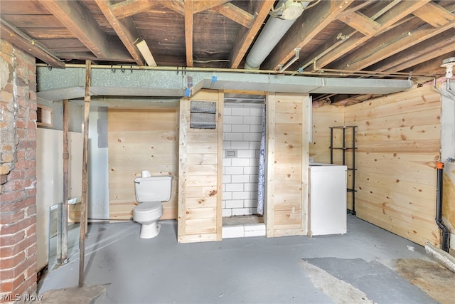 basement featuring wood walls and washer / dryer