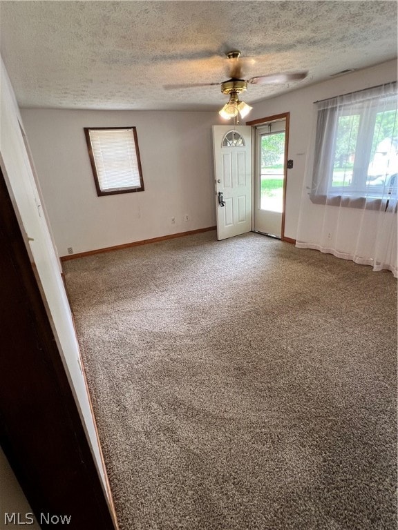 empty room featuring a textured ceiling, ceiling fan, and carpet flooring