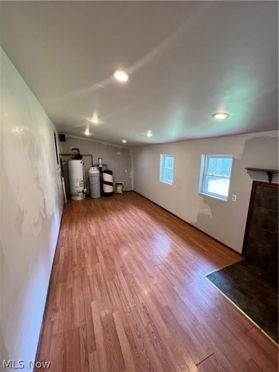 basement with water heater and wood-type flooring