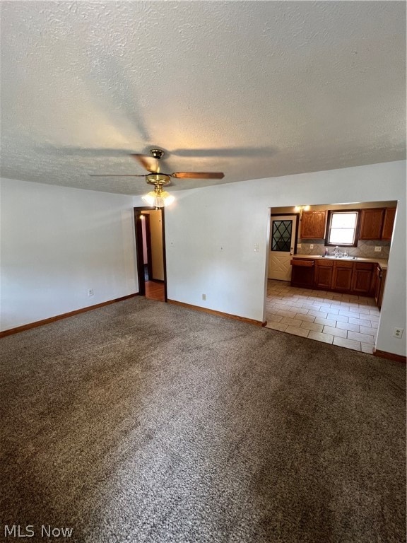 unfurnished living room featuring a textured ceiling, sink, light tile patterned floors, and ceiling fan