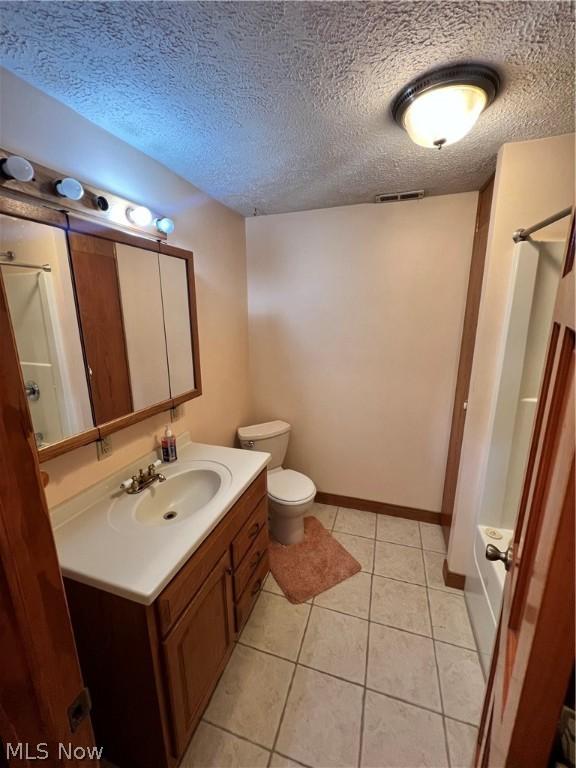 bathroom featuring tile patterned flooring, toilet, vanity, and a textured ceiling