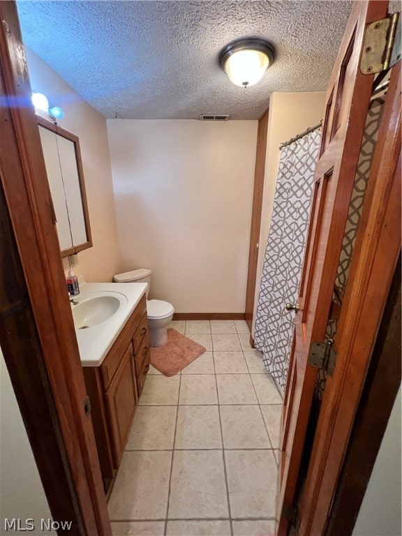 bathroom featuring vanity, a textured ceiling, tile patterned flooring, and toilet