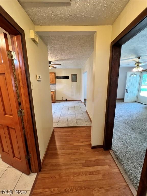 hall with a textured ceiling and light hardwood / wood-style floors