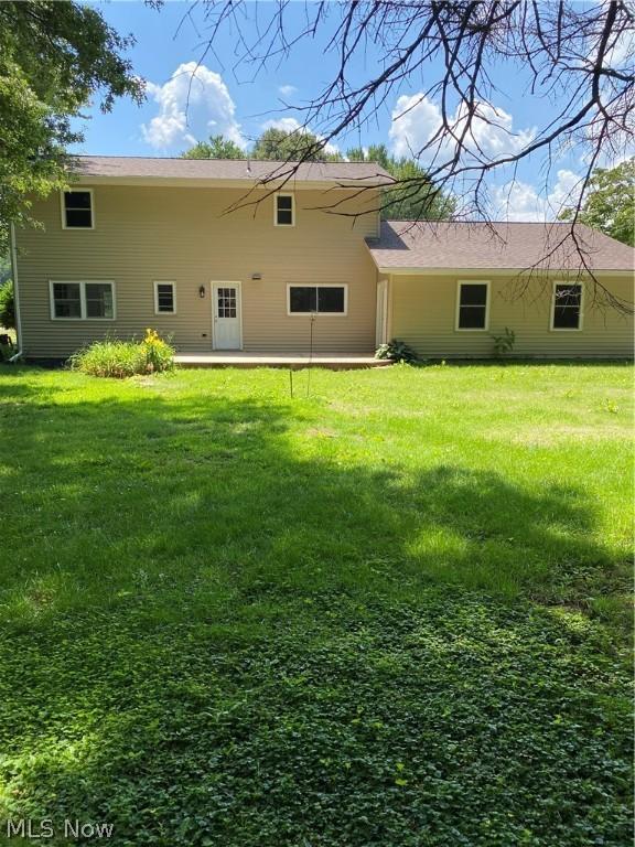 back of property with a yard and a patio area