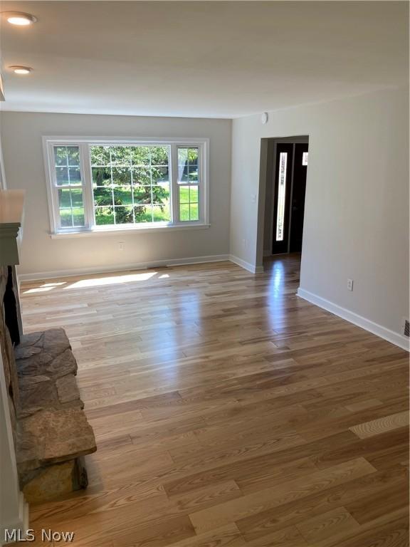 unfurnished living room featuring light wood-type flooring and a fireplace