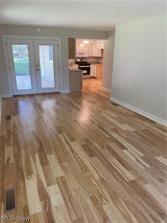 unfurnished living room with french doors and light hardwood / wood-style flooring