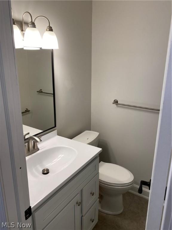 bathroom featuring tile patterned flooring, vanity, and toilet