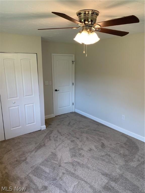 unfurnished bedroom featuring carpet, ceiling fan, and a closet