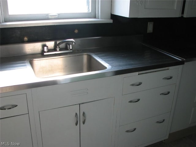 kitchen featuring decorative backsplash, white cabinetry, and sink