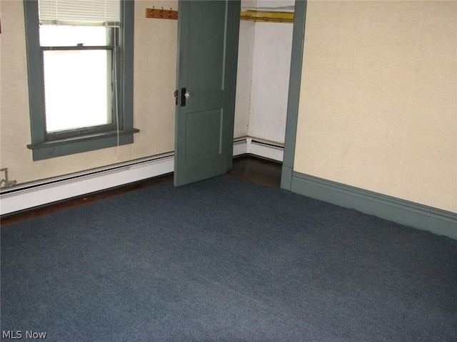 unfurnished bedroom with dark colored carpet, baseboard heating, and a closet