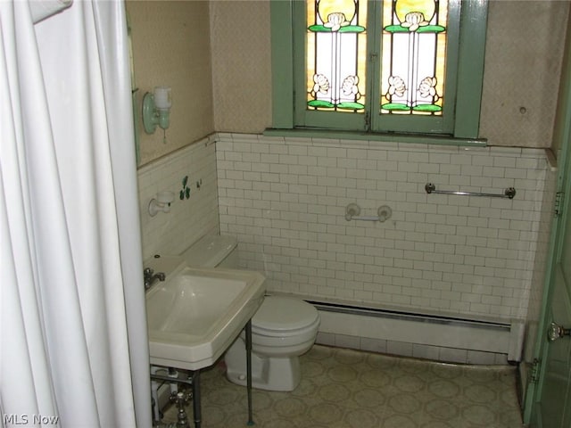 bathroom with toilet, sink, tile walls, and a baseboard radiator