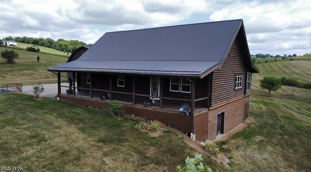 back of property featuring a rural view, a yard, and covered porch