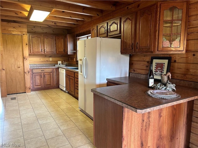 kitchen featuring beamed ceiling, white appliances, wooden walls, and kitchen peninsula