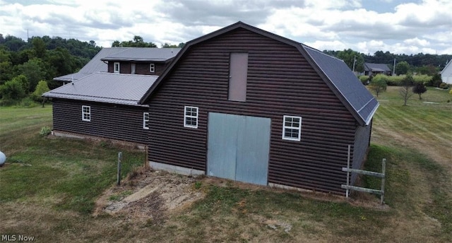 view of side of property featuring a gambrel roof, a lawn, and metal roof