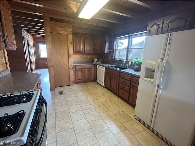 kitchen featuring white appliances, sink, and wood walls