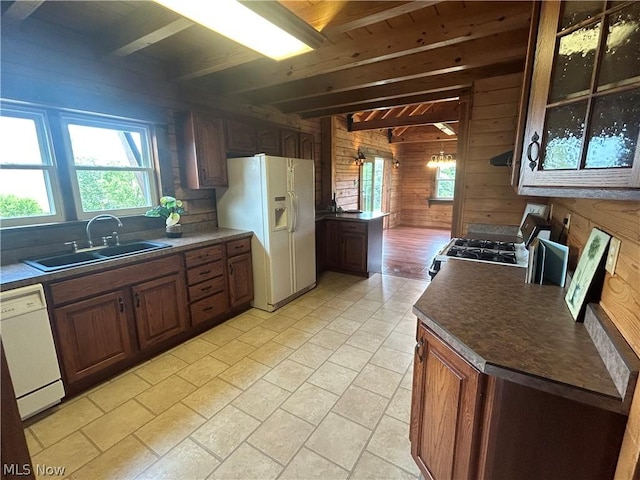 kitchen featuring white appliances, beam ceiling, sink, and wood walls