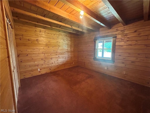 empty room with beamed ceiling, carpet flooring, wood ceiling, and wooden walls