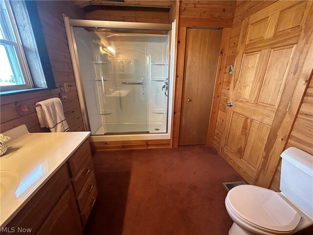 bathroom featuring vanity, toilet, an enclosed shower, and wood walls