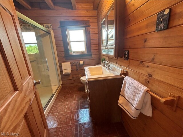 bathroom with vanity, wooden walls, a shower with shower door, and toilet