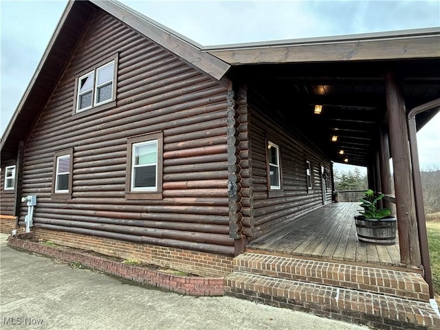 view of side of property with log siding and covered porch