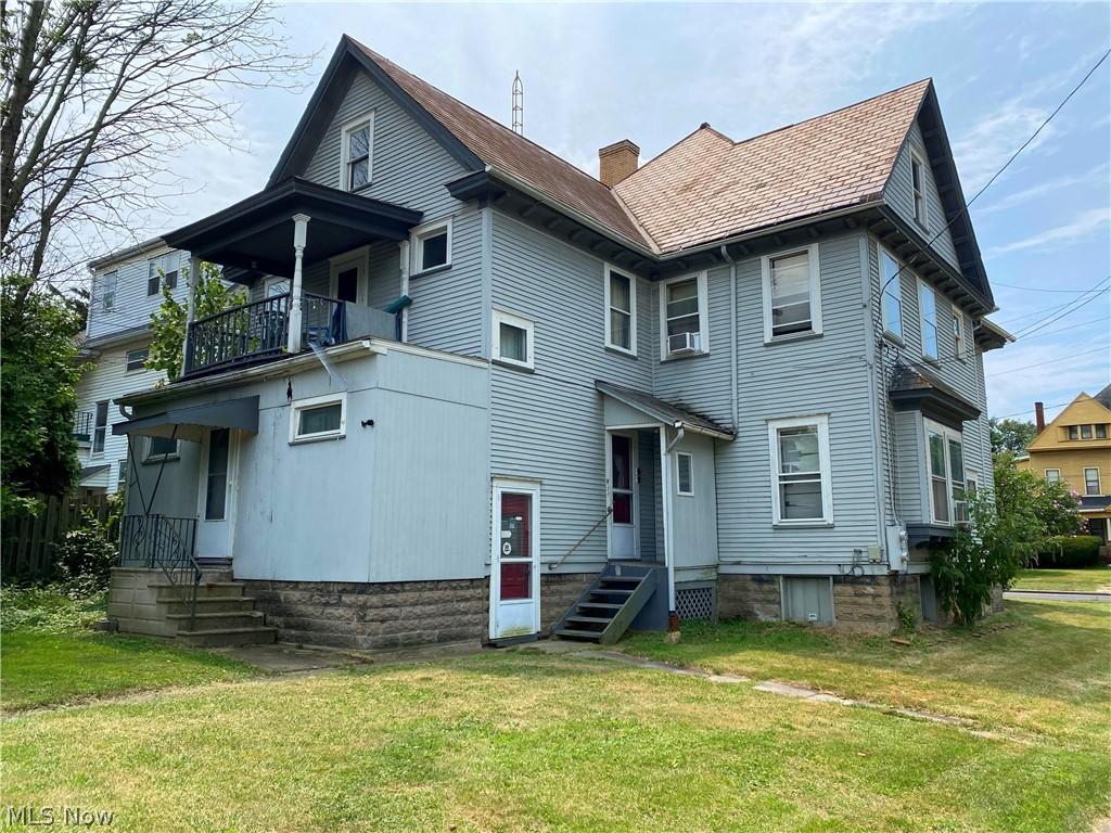 rear view of house featuring a balcony and a yard