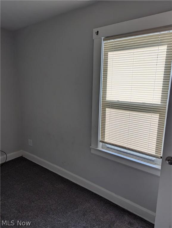 unfurnished room featuring dark carpet