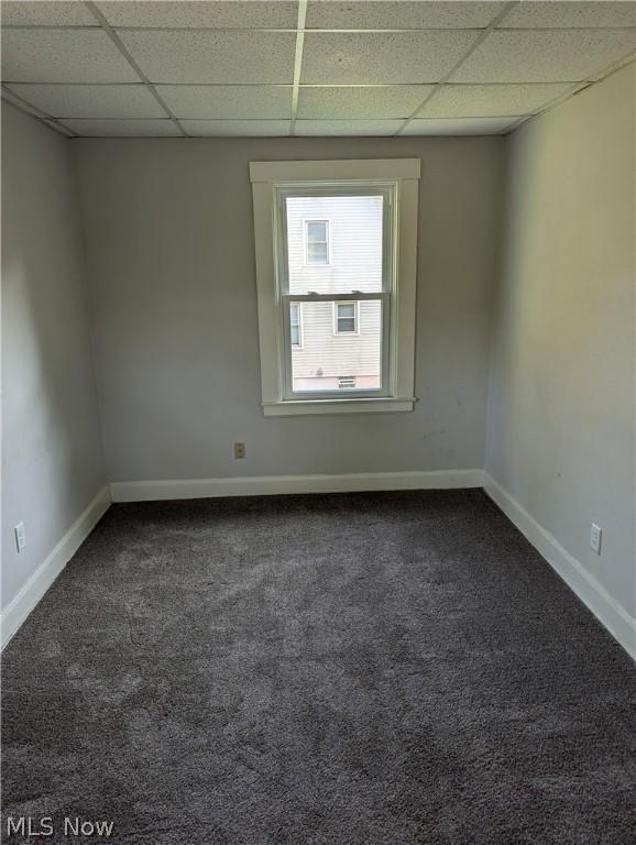 carpeted empty room with a drop ceiling