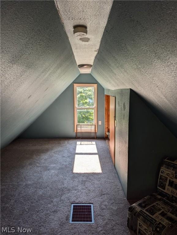 bonus room with a textured ceiling, carpet, and lofted ceiling