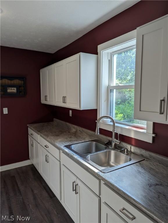 kitchen featuring white cabinets, dark wood-type flooring, and sink