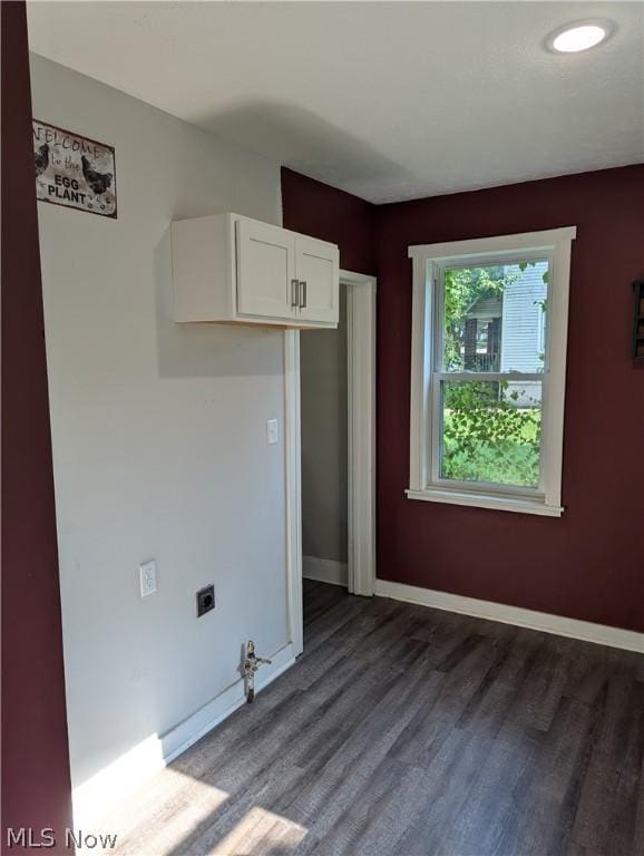 laundry area with electric dryer hookup, cabinets, and wood-type flooring