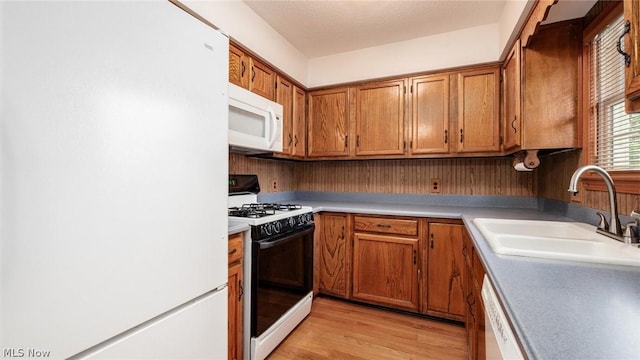 kitchen with sink, white appliances, and light hardwood / wood-style flooring