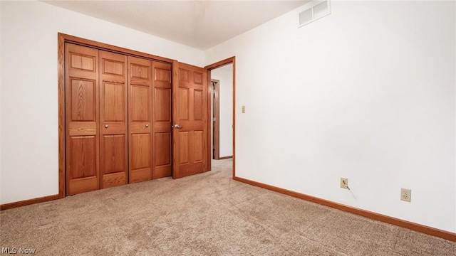 unfurnished bedroom with a closet and light carpet