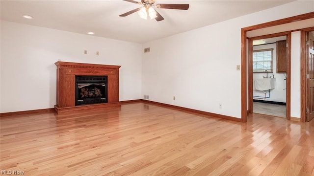 unfurnished living room featuring ceiling fan and light wood-type flooring