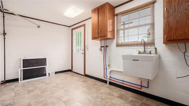 laundry area with cabinets, ornamental molding, and sink