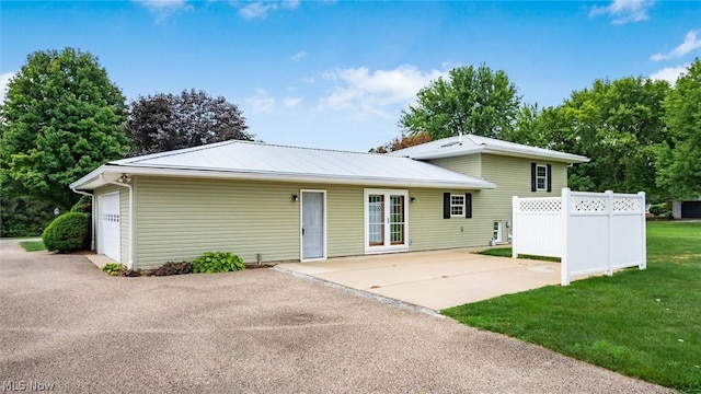 back of property featuring a garage, a lawn, and french doors