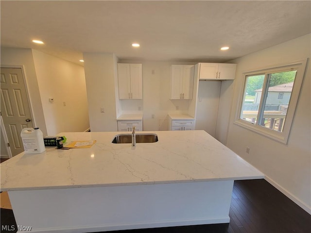 kitchen featuring light stone countertops, a kitchen island with sink, dark wood-type flooring, sink, and white cabinets