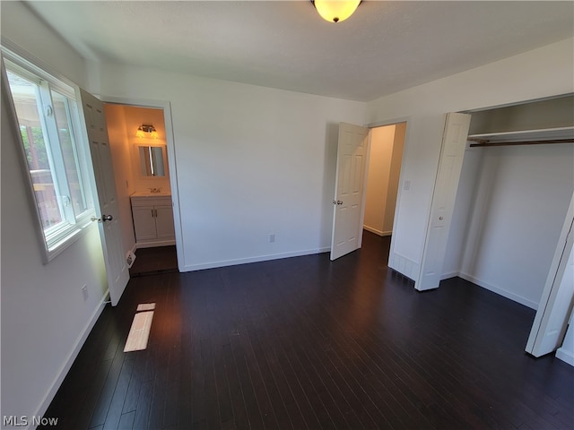 unfurnished bedroom featuring dark hardwood / wood-style flooring, ensuite bathroom, and a closet