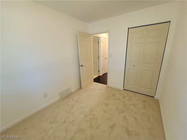 unfurnished bedroom featuring light carpet and a closet