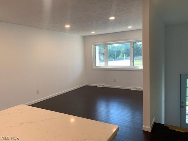 unfurnished room featuring dark hardwood / wood-style flooring and a textured ceiling