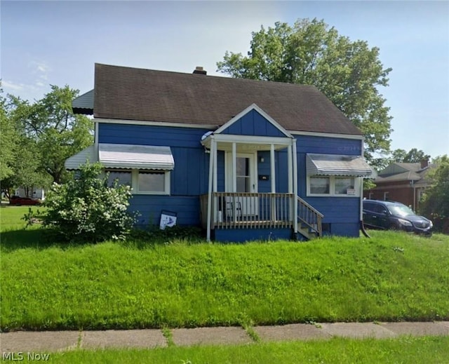 bungalow-style home featuring a front lawn and roof with shingles