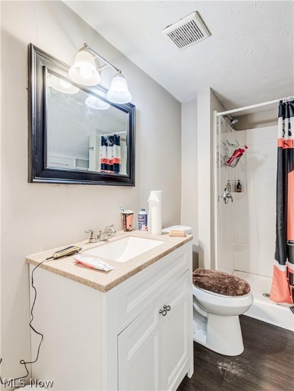 5521 W 48th St, Parma, OH 44134 - bathroom featuring vanity, a shower stall, a textured ceiling, visible vents, and wood finished floors
