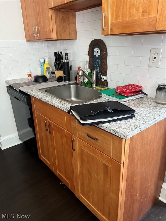 kitchen with sink, black dishwasher, light stone countertops, dark hardwood / wood-style floors, and backsplash