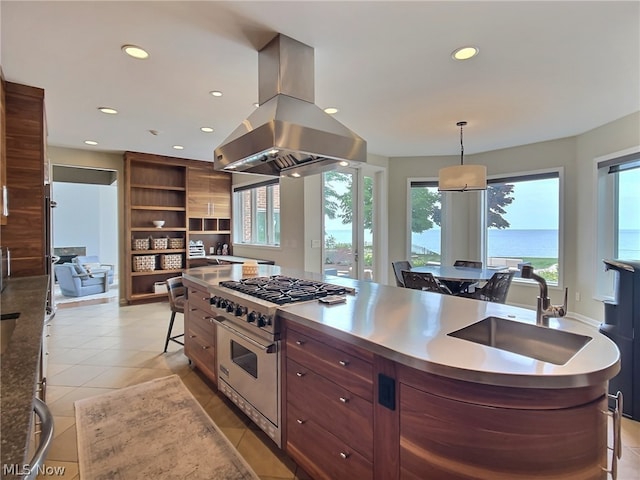 kitchen featuring sink, a water view, island range hood, decorative light fixtures, and stainless steel stove