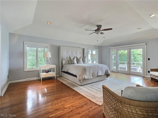 bedroom featuring access to exterior, a tray ceiling, wood-type flooring, and ceiling fan