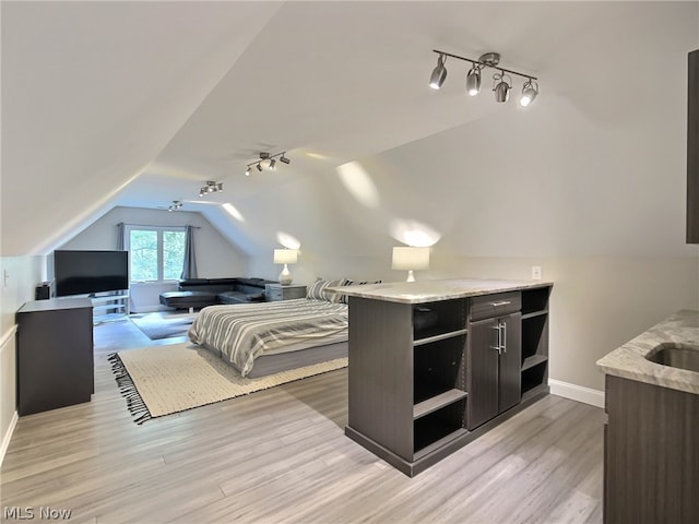 bedroom featuring lofted ceiling, sink, and light hardwood / wood-style floors