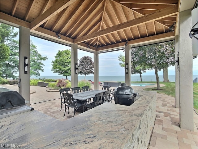 view of patio / terrace featuring a gazebo, a water view, and an outdoor kitchen