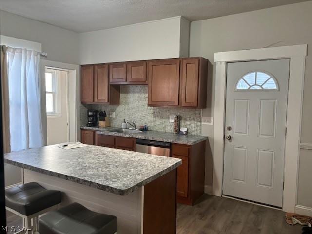 kitchen featuring dark hardwood / wood-style floors, a breakfast bar, tasteful backsplash, and a wealth of natural light