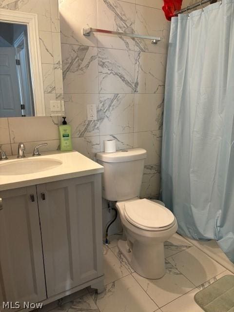 bathroom featuring tile patterned floors, vanity, tile walls, and toilet