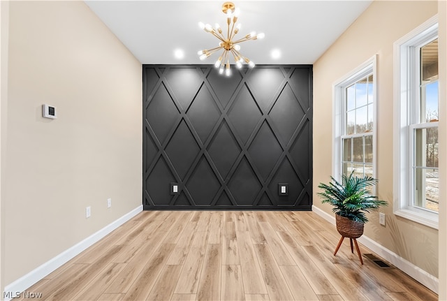 spare room with a notable chandelier and light hardwood / wood-style floors