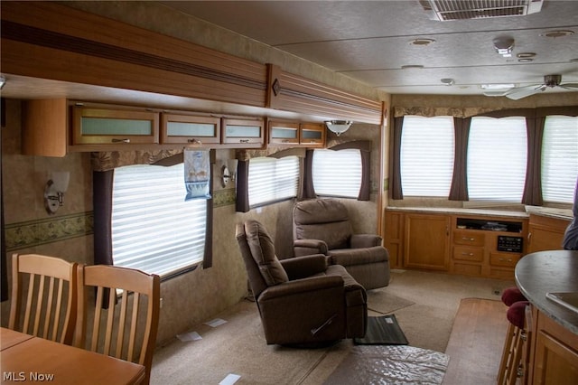 interior space with ceiling fan, visible vents, and light colored carpet